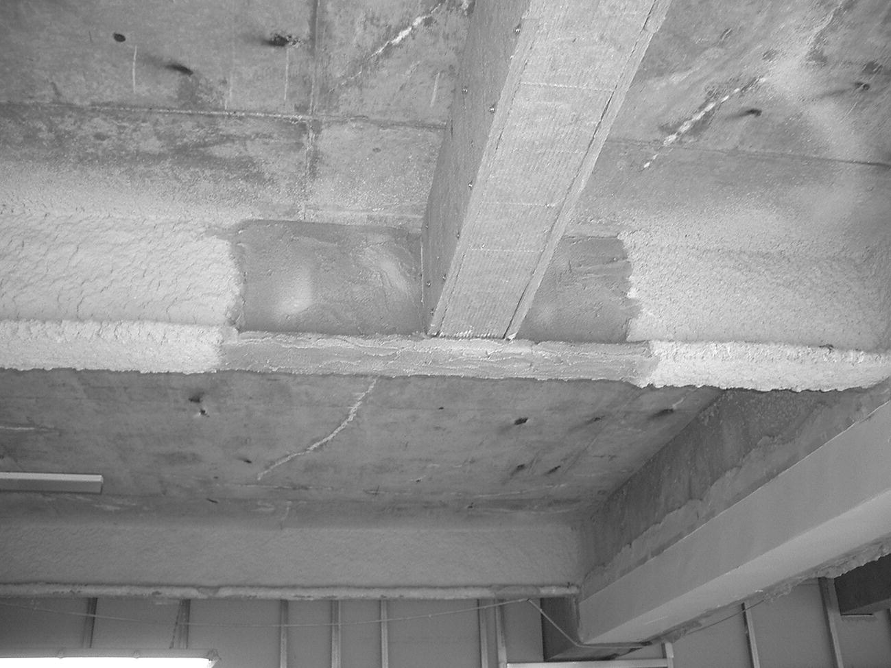 Photo of steel covered in mineral board fire protection connected to existing steel beam with vermiculite coating.