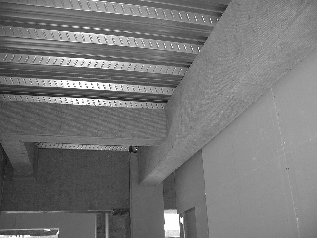 Photo displaying mineral fibreboard fire protection screwed to light steel framing around the steel sections.