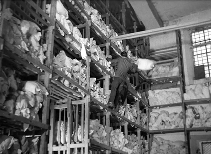 Figure 6.2 Bicycle Thieves (De Sica, 1948): camera movement instead of cutting. In Bicycle Thieves, De Sica uses camera movement to reframe action rather than cut, often to make a point. At the pawn shop, a wide shot tilts up to follow the clerk climbing a ladder, revealing that there are actually hundreds of pawned linens, the slow tilt revealing the immensity of the economic misery facing the Italian working class. Source: Copyright 1948 Ente Nazionale Industrie Cinematografiche.