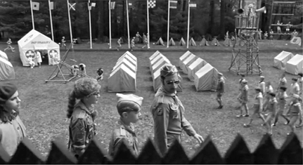 Figure 8.12 Internal rhythm: tracking shot in Moonrise Kingdom (Anderson, 2012). The sheer number of visual rhythms at work in this shot reflects Wes Anderson’s meticulous control of mise-en-scène. The steady march of Cousin Ben (Jason Schwartzman) and his entourage holding a fixed position relative to the camera, contrasts with a range of other visual rhythms in the background. Source: Copyright 2012 Focus Features.