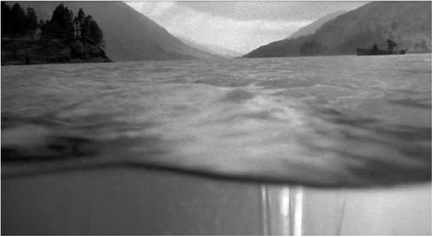 Figure 8.20 External rhythm: spatially integrated wipe in Highlander (Mulcahy, 1986). As the camera tightens and tilts upward to an aquarium located behind Connor MacLeod (Christopher Lambert), a rippling edge of water maps the incoming shot onto the aquarium in a “spatially integrated wipe.” As a result, the camera appears to rise from present day apartment/aquarium space into an ancient Scottish loch in an energetic way that the “lazy tranquility” of a simple dissolve could not. Source: Copyright 1986 20th Century Fox