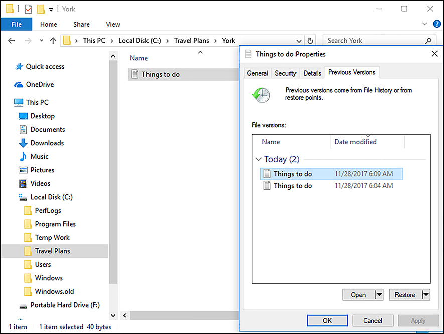 A screen shot of the Previous Versions tab on the properties page of a file called Things to do.txt. Listed in the middle of the page are two versions of the Test.txt file; the top one has a time modified of 6:09 AM and the second file has a timestamp of 6:04 AM. At the bottom of the dialog box are two options: Open and Restore.