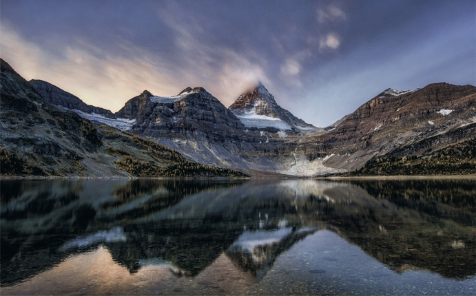 3.3 The delicate pink of alpenglow graces the clouds surrounding the peak of Mt. Assiniboine in the Canadian Rockies.