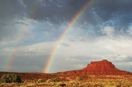 Photo of rainbow formed in a hilly area of a deset.