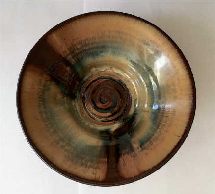 Photo shows different hues in curved shapes present in a hand-thrown bowl.
