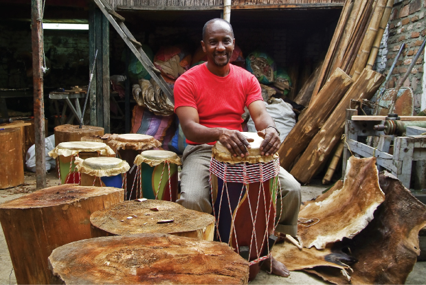 Photo showing a man seated in his musical instruments workshop.
