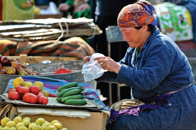 Photo of a woman running a vegetable shop is seen holding a plastic cover in her hands.