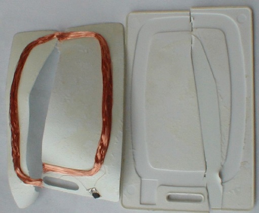 Photograph shows a passive proximity card with the plastic casing opened to show components such as antenna coil and integrated circuit.