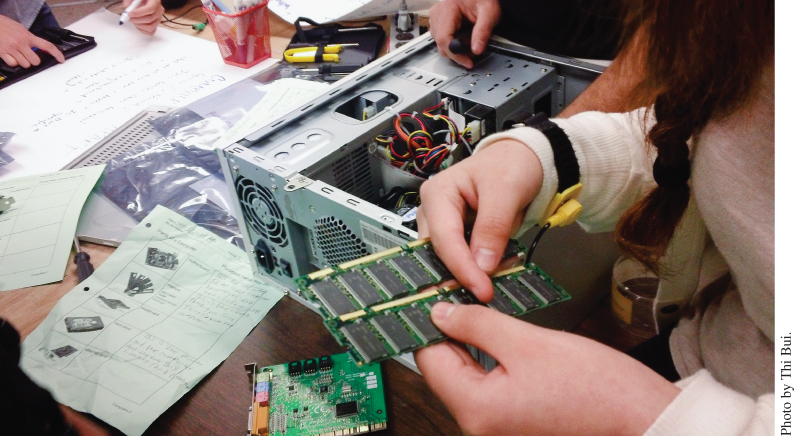 Photo displaying students handling computer components.