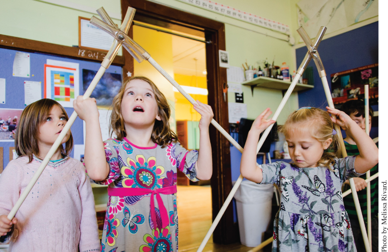 Photo displaying 3 kindergarten students handling interlinked rods in order to build a geodesic dome.