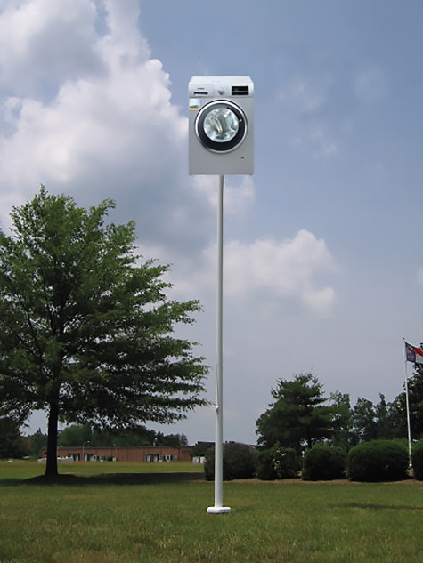 Photo depicting a large washingmachine on the top of a flagpole.