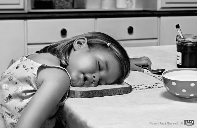 Image shows a small girl sleeping on the table with a spoon on the left hand.
