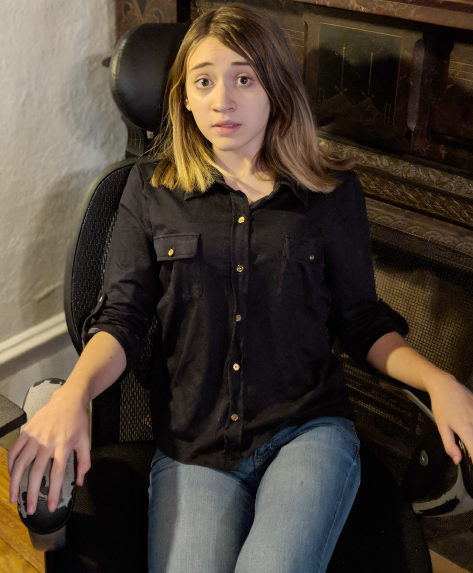 Photograph of a girl seated on an armchair displaying a startled fear on her face and body.