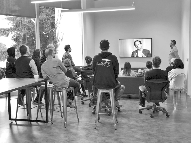 Photo illustration of people of the Whil team, seated in chairs watching a TV lecture program on mindfulness practice.