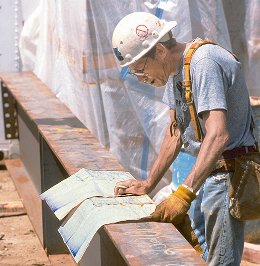 Photograph of a project engineer examining a blue print.