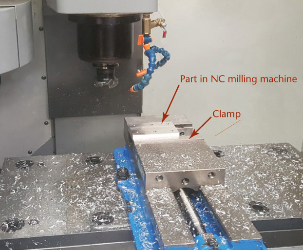 Photograph shows a part clamped in NC milling machine. The left corner of the part is 0, 0, and 0 during the process.