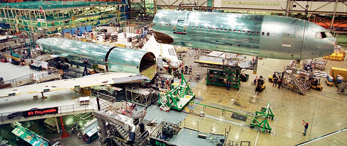 A photograph shows the assembly of an aircraft in a manufacturing environment.