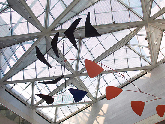 Photograph of Calder Mobile Hanging from a Glass Ceiling designed in a spider web fashion.