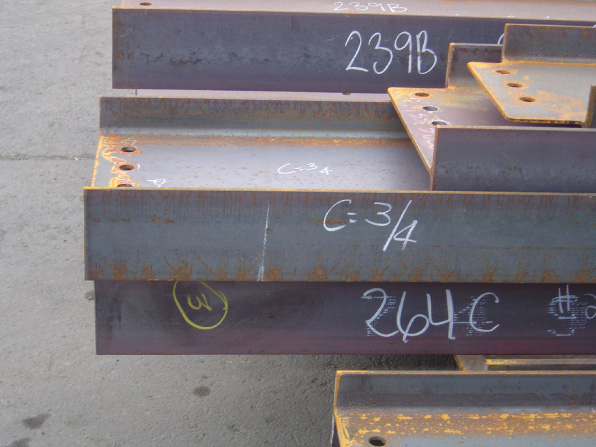 Photograph of several Steel Beam Fabricators with Piece Marks on each beam. The markings read 239B, C equals 3 over 4, and 264C.