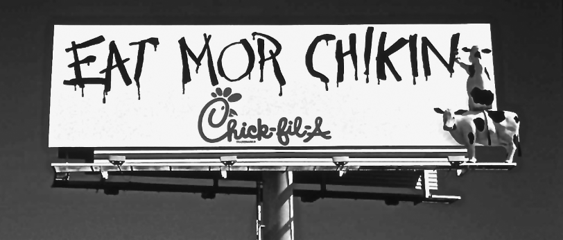 Figure representing a billboard ad for Chick-fil-A, depicting a cow sitting on another cow writing “Eat mor chikin.”
