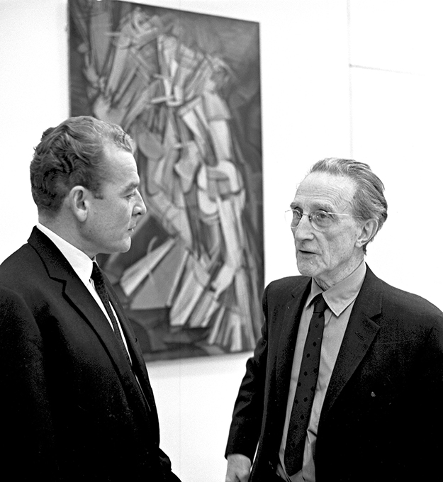A photograph shows Marcel Duchamp and a person discussing his abstract painting.
