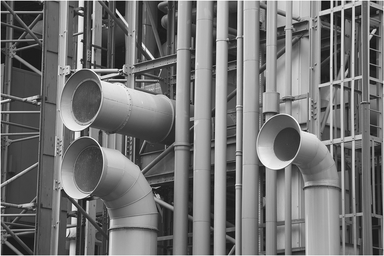 Pipes in an industrial setting with three large pipes opening to the left.