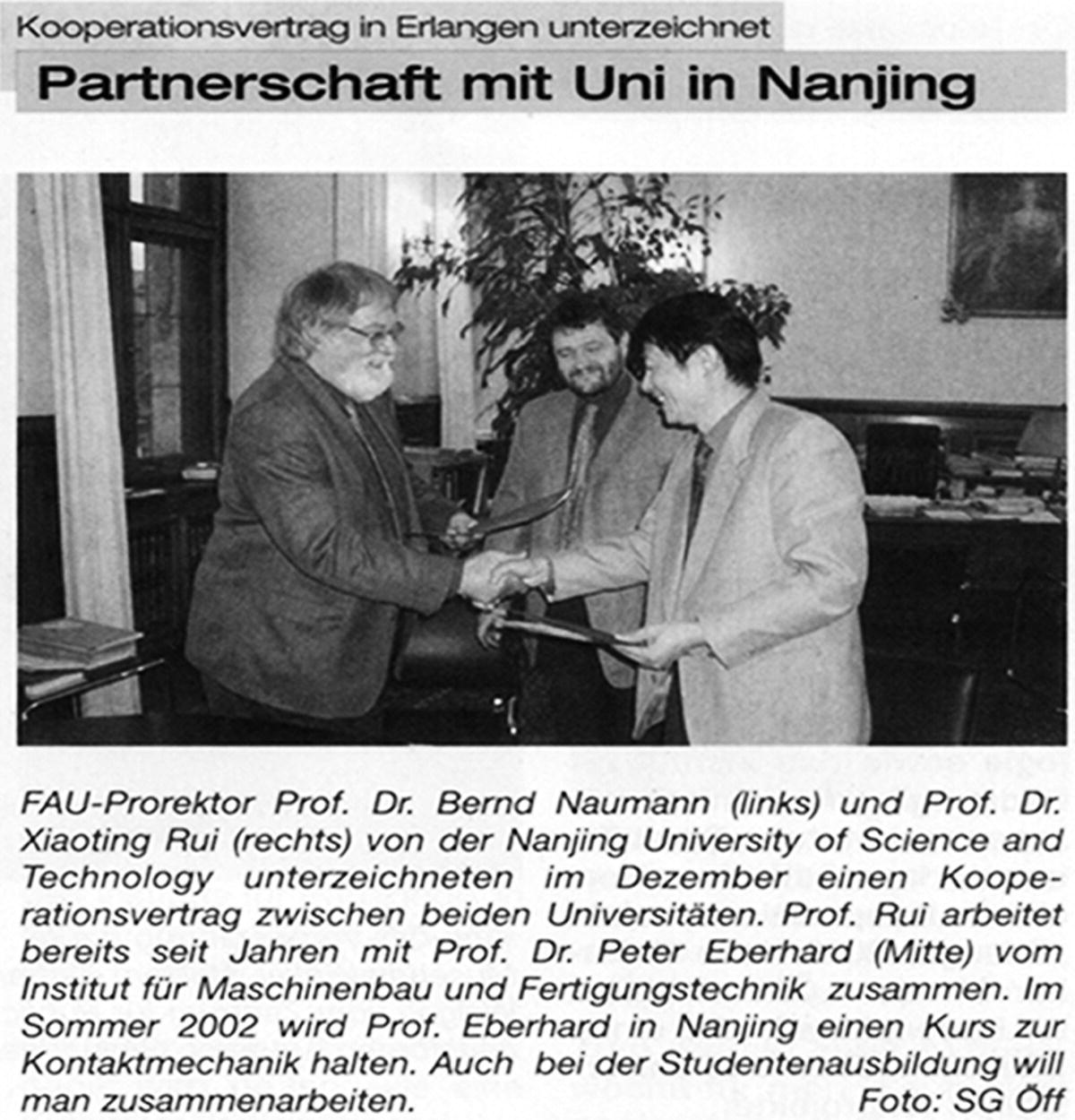 Snipped image from a newspaper, displaying Professor Xiaoting Rui (right) and the president of Erlangen-Nurnberg University (left) shaking hands. To the right of Professor Xiaoting Rui is another man smiling.