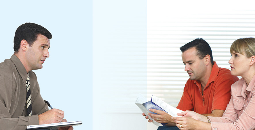 A photo shows a salesperson in a discussion with a couple. He holds an open book and pen in hand.