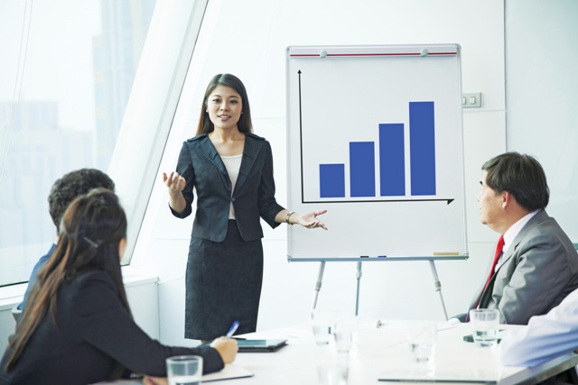 A photo shows a sales presentation in progress. A woman presents a bar graph on the whiteboard behind.