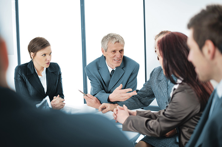 A photo shows a man talking in a meeting.