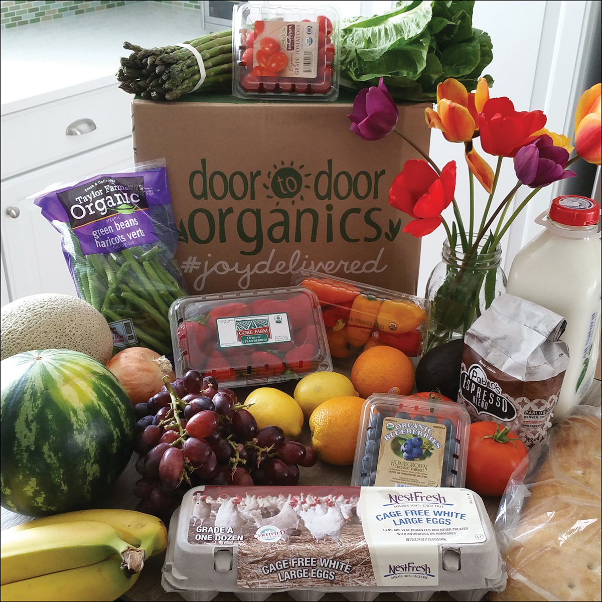 A photo shows a variety of fruits and vegetables from Door to Door Organics store.