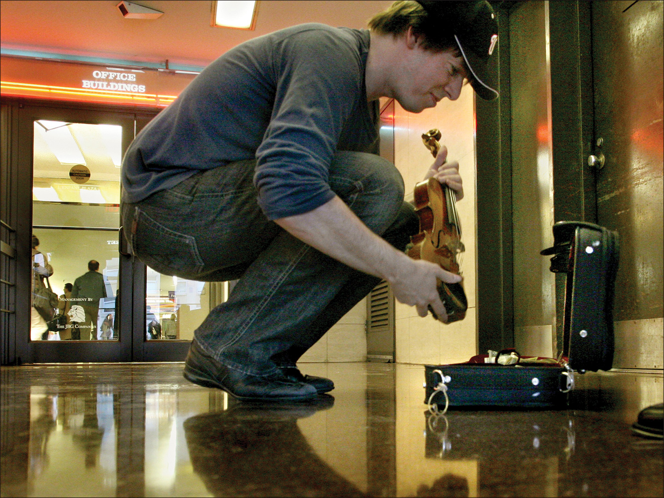 A photo shows Joshua Bell placing his violin back into its case at a Metro Station.