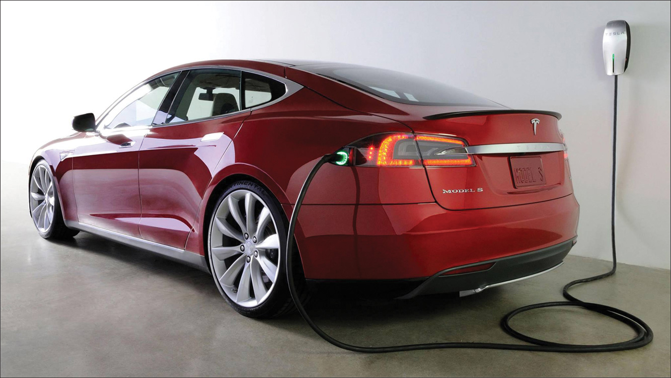 A photo shows a Tesla sedan being charged from an electric outlet.