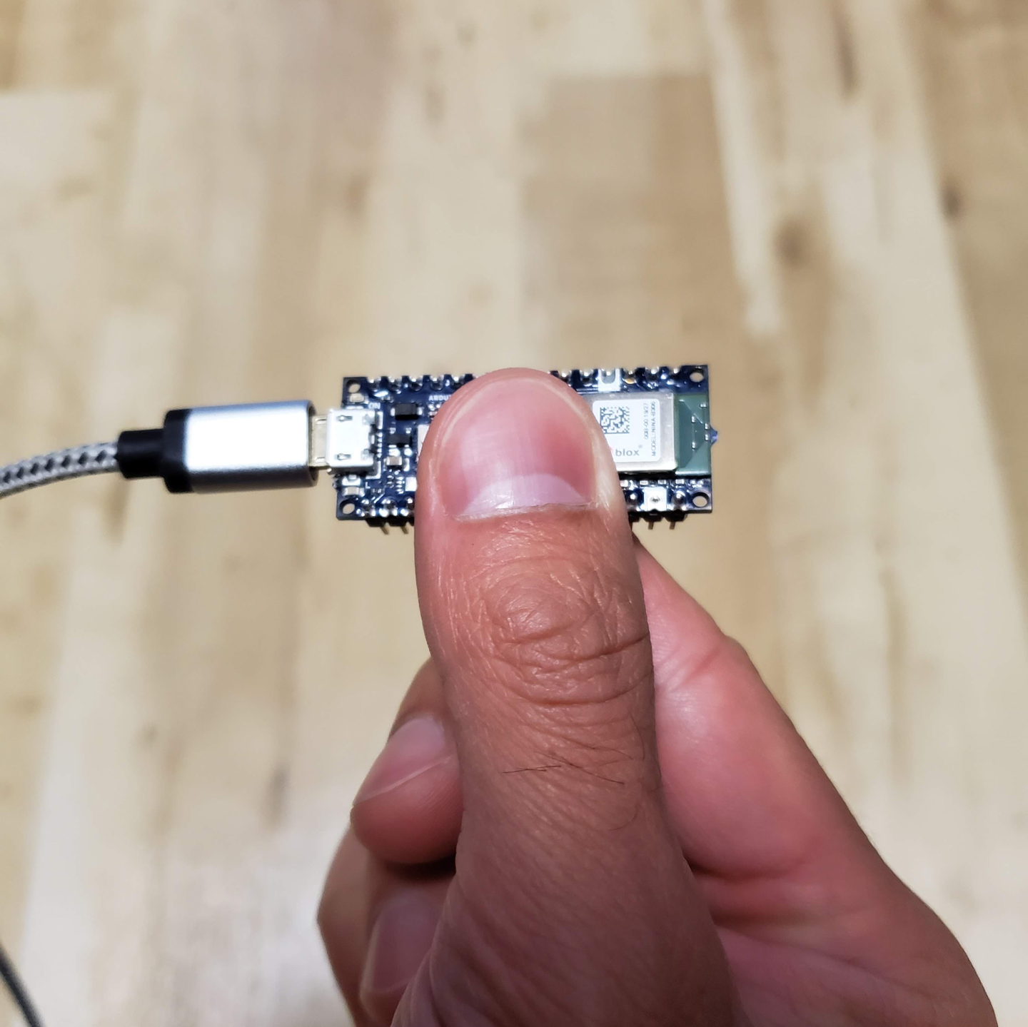 Photo of a hand holding an Arduino Nano 33 BLE Sense board