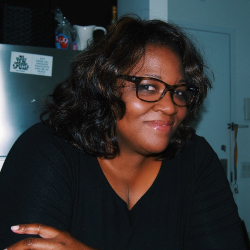 Photo illustration of an African American woman wearing spectacles and smiling at the viewer.