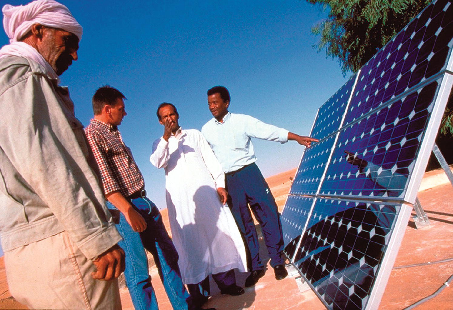 A group of men standing in front of the solar panel.
