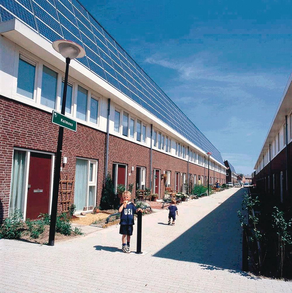 Social housing with solar panels on the roofs and children on the street.
