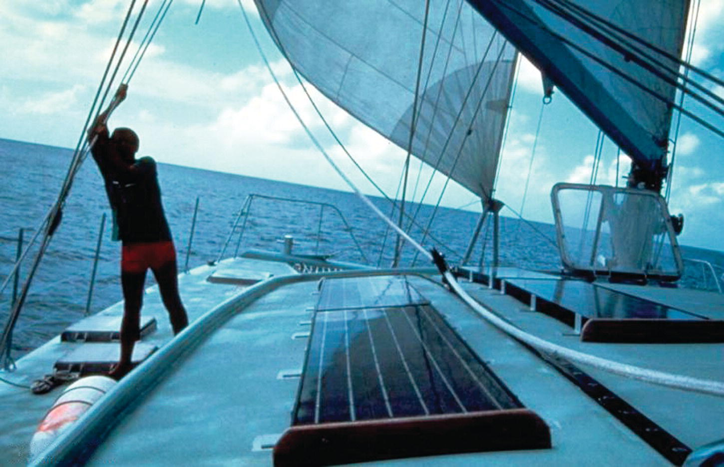 A yacht with PV modules installed on the decks, with a man standing on the left side.
