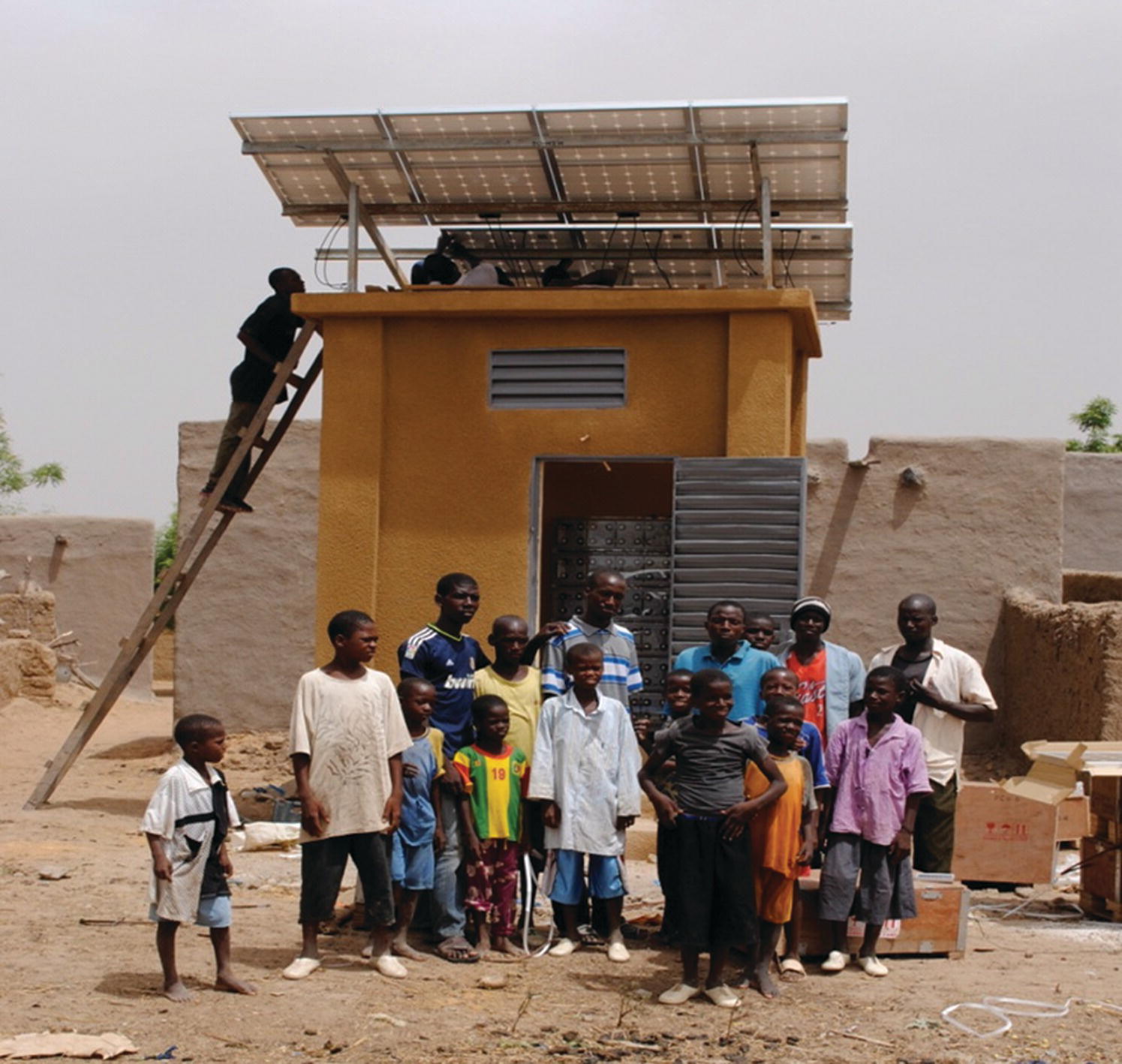 A group of people standing in front of the sharedsolar mini‐grid installation during construction phase.